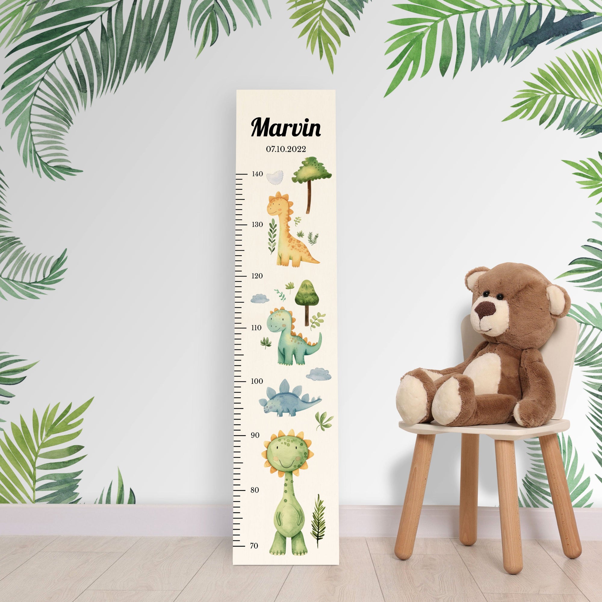 Personalisierte Messlatte aus Holz für Jungen oder Mädchen mit Dinos vor einer Kinderzimmerwand. Personalisierte Messlatte aus Holz für Jungen oder Mädchen mit Dinos vor einer Kinderzimmerwand.